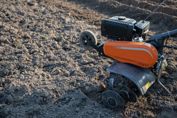 small plowing machine in hands of a farmer making arable in black soil