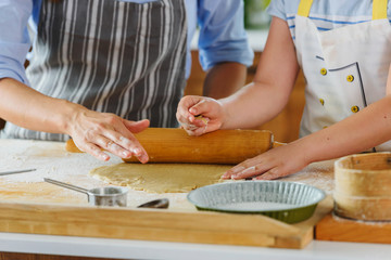 Mother and daughter making apple pie in the kitchen. Teaching child to help at home