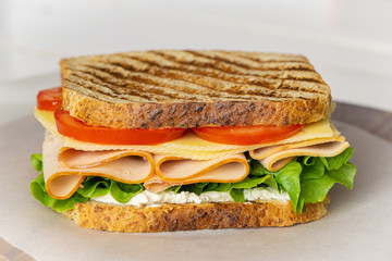 Club sandwich with ham, cheese, lettuce, and tomato. Tasty homemade lunch, breakfast or take away food. 