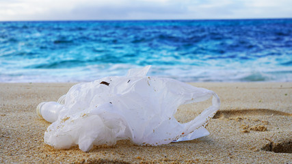 Plastic trash in blue ocean water on the sand. bottles and plastic bags on the sea beach. ocean pollution