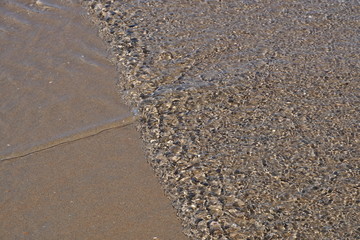 Das Meerwasser kommt in kleine Wellen und erzeugt eine Textur aus kleine Schatten. Auf dem Sand  kommt noch eine ganz kleine Strömung und unterteilt der linke untere Teil des Bildes noch einmal durch.