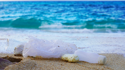 Plastic trash in blue ocean water on the sand. bottles and plastic bags on the sea beach. ocean pollution