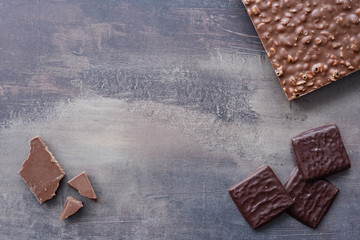 Top view of different types of chocolates - dark and milk. Chocolate bar with nut filling. Sweets on marble table background.