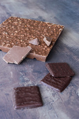 Vertical photo of chocolates. Different types of chocolate - dark and milk. Chocolate bar with nut filling. Sweets on marble table background.