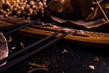 Stick holder and incense stick with leaves and flowers on black background