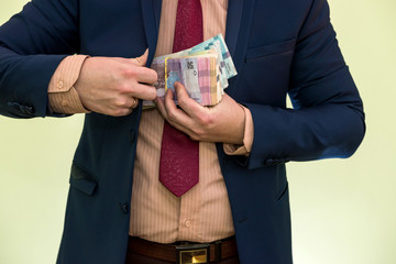 Business man hiding pack of Ukraine in suit pocket. The concept of corruption and fraud. UAH. 1000 new hryvnia banknotes