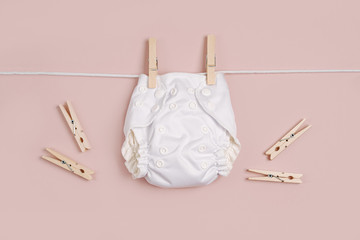 Reusable cloth baby diapers drying on a clothes  line. Eco friendly cloth nappies on a pink...