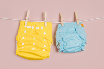 Reusable cloth baby diapers drying on a clothes  line. Eco friendly cloth nappies on a pink...
