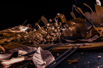 Stick holder and incense stick with leaves and flowers on black background