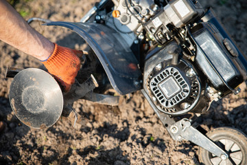 small plowing machine in hands of a farmer making arable in black soil