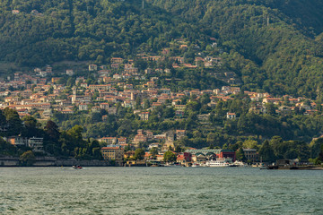 Como, ITALY - August 4, 2019: Apartments, villas, hotels on the green forested mountainsides near Lake Como. Beautiful Italian Como city. Warm sunny summer day in very popular holiday destination