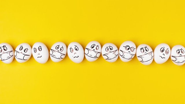 White eggs with painted faces in respiratory masks move on a yellow background. Emotions on the eggs. Stop motion animation