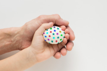 Hand of a child and an adult holding an Easter egg