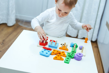 baby boy plays with educational toy. toddler play with a wooden toys at home. Toddler play with a color educational toy. Child play at the table in the baby room. Child development. 