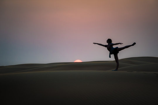 Silhouette Woman Practicing Ballet At Desert Against Sky During Sunset