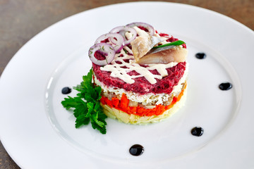 herring salad under a fur coat, on plate decorated with parsley, close-up