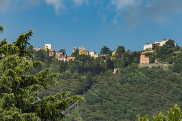 Fototapeta na wymiar Como, ITALY - August 4, 2019: Apartments, villas, hotels on the green forested mountainsides near Lake Como. Beautiful Italian Como city. Warm sunny summer day in very popular holiday destination