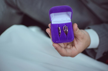 wedding rings in a purple box from the hands of the groom