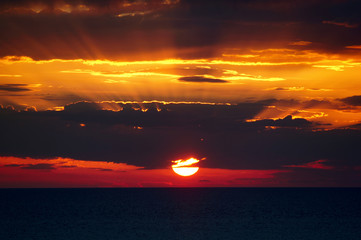 Colorful sunset over the Black Sea.Yellow sunbeams shine from the red sun over a blue cloud