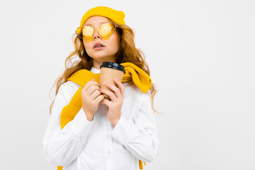 girl in winter hat and scarf with a glass of hot drink in her hands on a white background with copy space