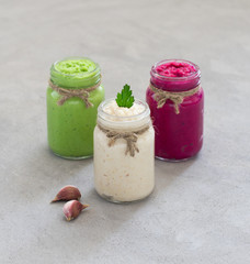 Russian appetizer horseradish with beetroot, green horseradish wasabi, white horseradish with lemon in jars on a light background