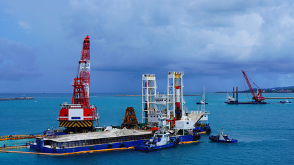 a floating crane platform extracts white sand from the bottom of the Pacific Ocean. sand mining industry in japan. unusual blue turquoise color of water in the ocean