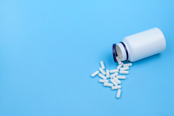 White pills on a blue background. Medical concept close up with space for text