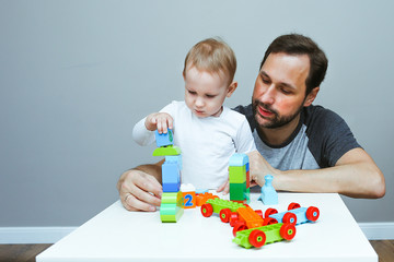 baby boy is playing with dad. father and son assemble the constructor. educational games