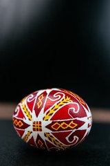 Colored red egg on bright black background. Easter holiday concept