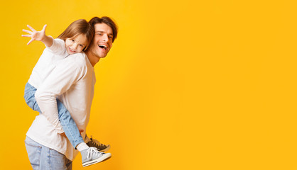Positive dad holding his happy daughter on his back