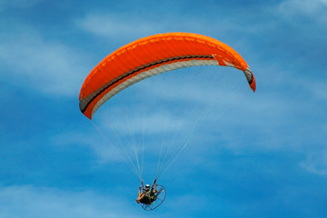 Parapente laranja isolado no céu de Salvador.