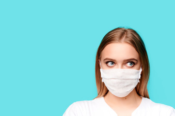 Young woman in a protective mask on an isolated background, isolated blue background, copy space