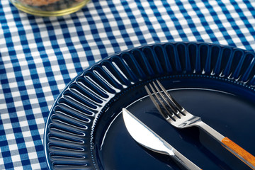 Deep blue ceramic plate with cutlery close up on table