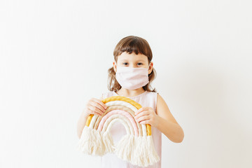 let's all be well. child at home wear reusable textile mask hold textile handmade rainbow.