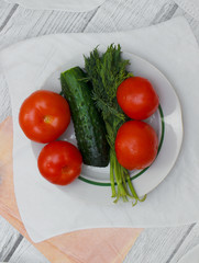 Vegetables tomatoes cucumber and dill on a plate