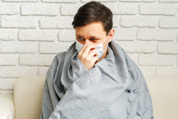 Caucasian man staying at home during Coronavirus / Covid-19 quarantine wearing medical mask