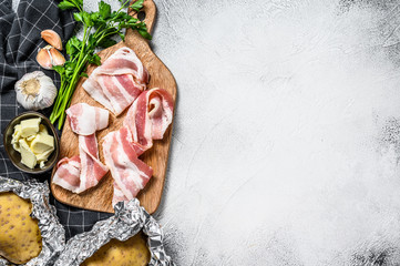 Ingredients for cooking baked potatoes with bacon, butter, parsley and cheese. Gray background. Top view. Copy space