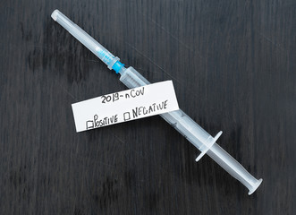 Medical syringe and the inscription coronavirus, on a black background, top view.
