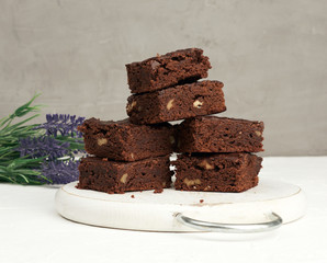 stack of square baked slices of brownie chocolate cake with walnuts