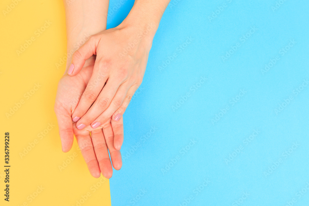 Wall mural female manicure. beautiful young woman's hands on pastel color background - image