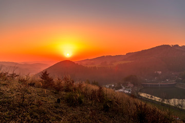 Close up sunset timelapse when sun is behind hills and mountains full of trees and moving clouds behind which sun sets a strong yellow-orange color view of the surrounding nature Beskydy Mountains