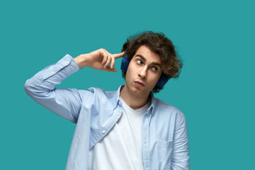 Naklejka premium Portrait of a young beautiful man wearing white t-shirt and blue shirt in headphones over blue background