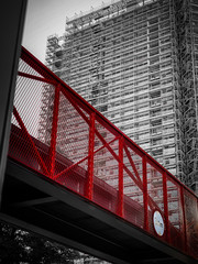 Czerwone ogrodzenie nadziemnego chodnika z budynkami mieszkalnymi w tle