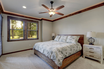 Bedroom interior with beige walls and wood trim and ceiling fan.