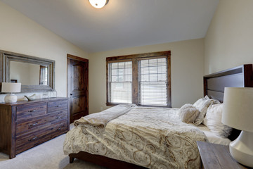 Bedroom interior with beige walls and wood trim and natural tone bedding.