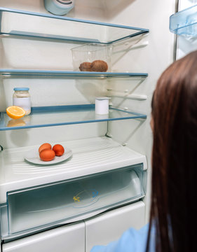 Worried Girl Looking At The Almost Empty Fridge Due To A Crisis