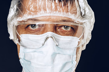 Male doctor wearing protective Mask and Goggles. Dark background. Close up