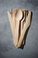 Disposable wooden cutlery on a stone table.
