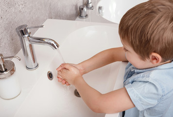 A little boy washes his hands with antibacterial soap. Coronavirus concept. The child protects his health.