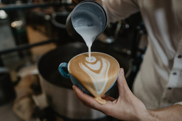 mano de barista haciendo un dibujo de corazón en una taza de café derramando café sobrante, semejante a salvador dalí - obrazy, fototapety, plakaty